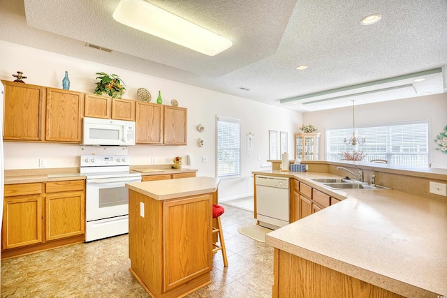 kitchen with white appliances, a sink, an island with sink, a textured ceiling, and plenty of natural light
