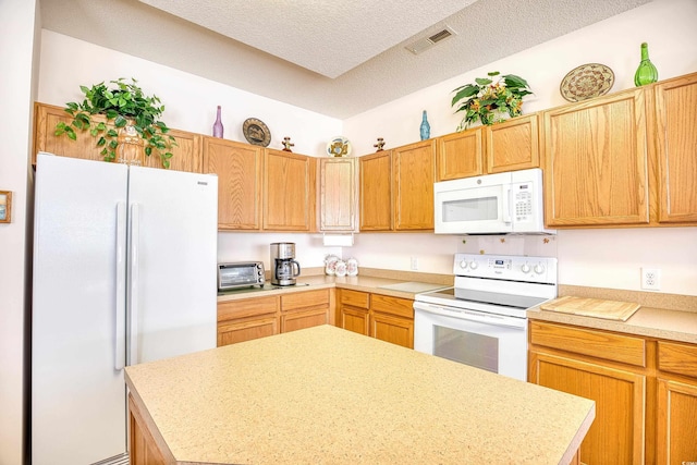 kitchen with white appliances, light countertops, a textured ceiling, and a center island