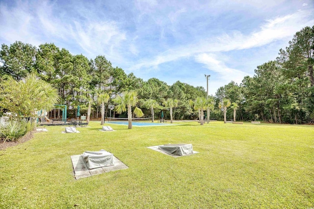 view of community featuring a yard and view of wooded area