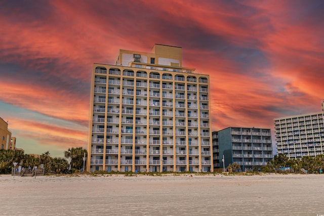 outdoor building at dusk with a water view and a view of the beach