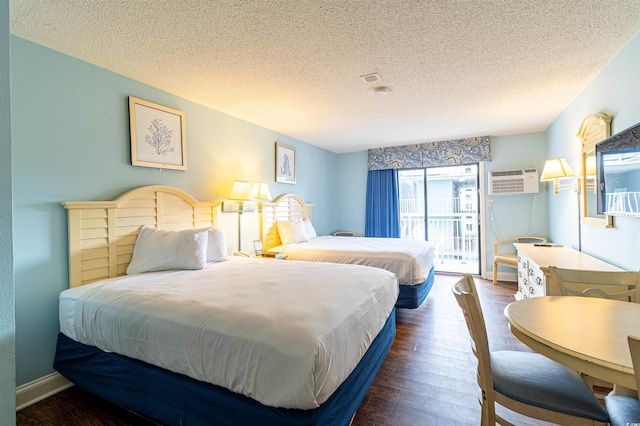 bedroom featuring access to exterior, a textured ceiling, dark hardwood / wood-style floors, and a wall mounted air conditioner