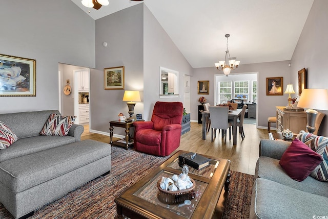 living room featuring ceiling fan with notable chandelier, high vaulted ceiling, and light hardwood / wood-style floors