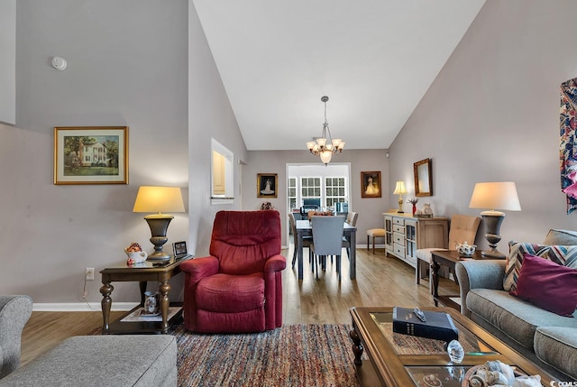 living room featuring a notable chandelier, high vaulted ceiling, and light hardwood / wood-style floors