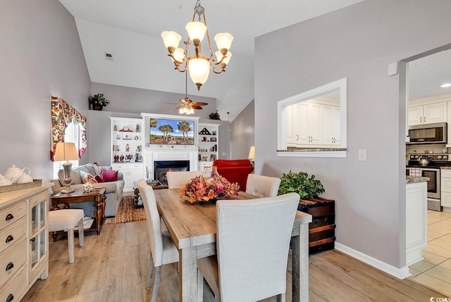 dining area with ceiling fan with notable chandelier, light hardwood / wood-style flooring, and vaulted ceiling