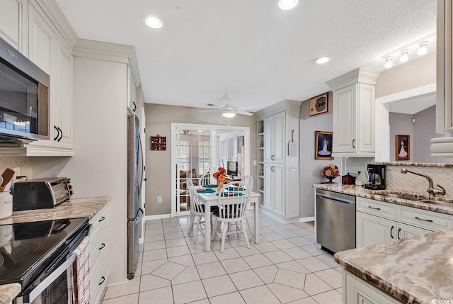 kitchen featuring decorative backsplash, sink, stainless steel appliances, light stone countertops, and white cabinets