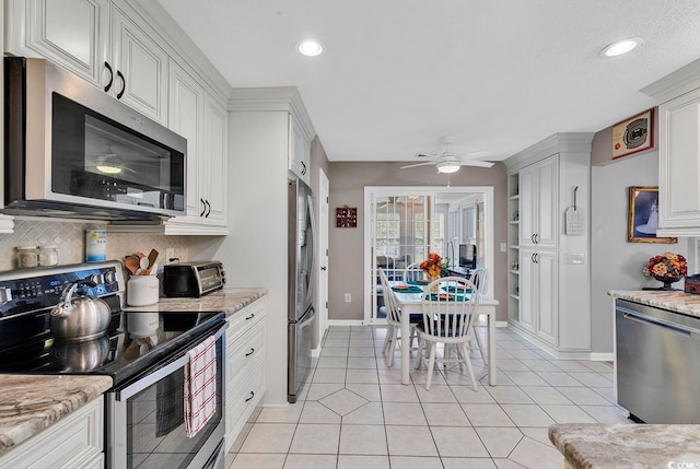 kitchen featuring light stone counters, ceiling fan, stainless steel appliances, tasteful backsplash, and white cabinetry