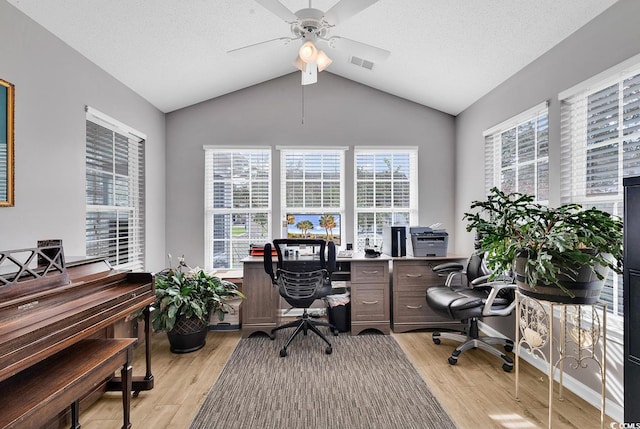 home office with ceiling fan, plenty of natural light, vaulted ceiling, and light hardwood / wood-style flooring