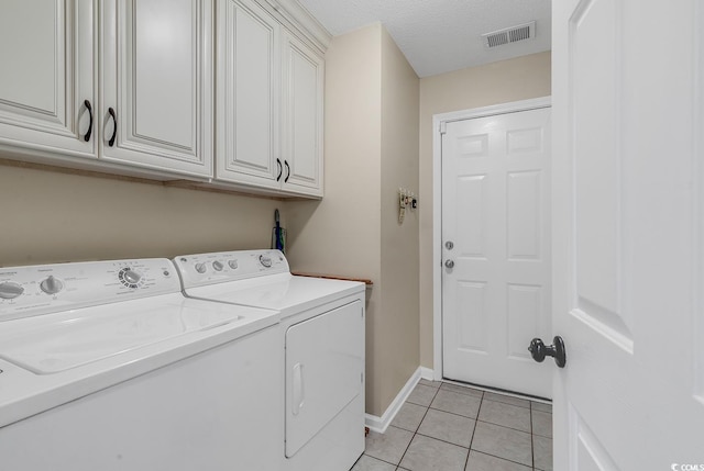 washroom with cabinets, separate washer and dryer, light tile patterned floors, and a textured ceiling