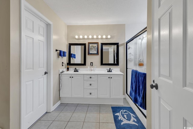 bathroom with tile patterned floors, a shower with shower door, vanity, and a textured ceiling