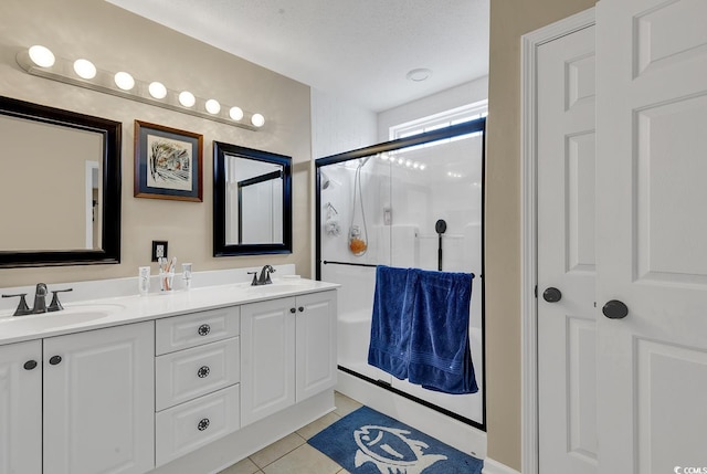 bathroom featuring tile patterned flooring, a shower with shower door, vanity, and a textured ceiling