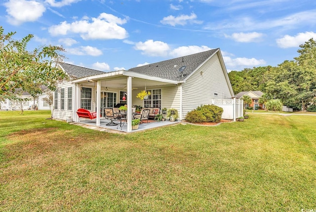 rear view of property featuring ceiling fan, a yard, and a patio area