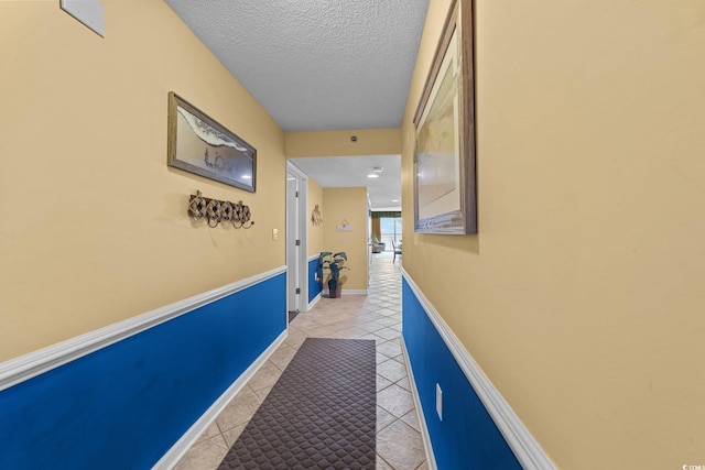 corridor with a textured ceiling and light tile patterned flooring