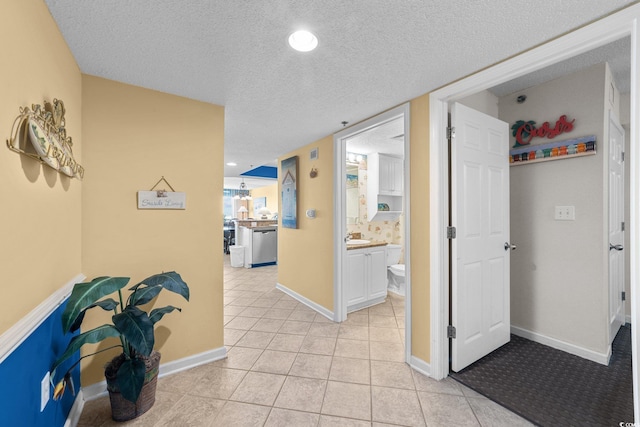 hallway with sink, a textured ceiling, and light tile patterned flooring