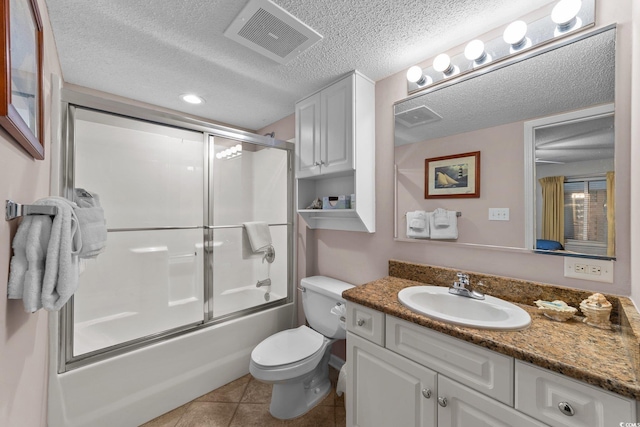 full bathroom with bath / shower combo with glass door, vanity, a textured ceiling, tile patterned flooring, and toilet