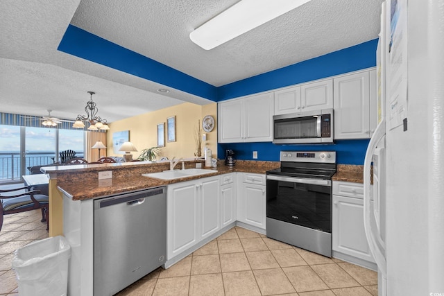 kitchen featuring kitchen peninsula, appliances with stainless steel finishes, a textured ceiling, sink, and white cabinetry