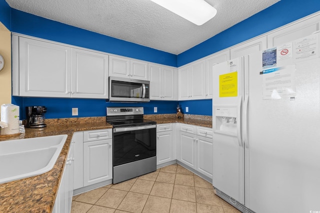 kitchen featuring white cabinets, stainless steel appliances, and a textured ceiling