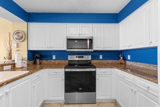 kitchen featuring a textured ceiling, stainless steel appliances, white cabinetry, and light tile patterned flooring