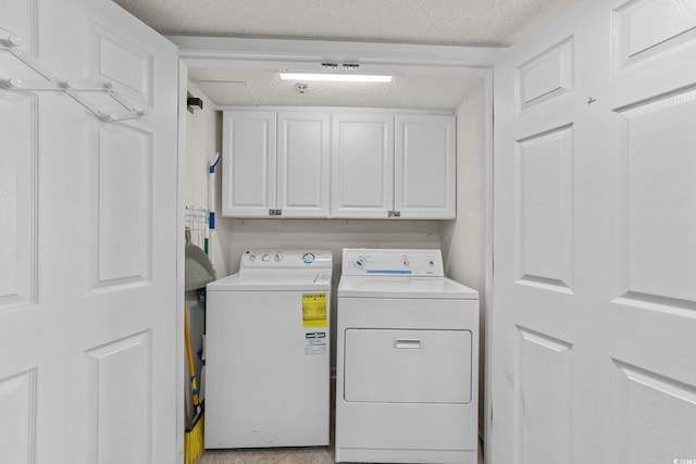 washroom with washer and clothes dryer, cabinets, and a textured ceiling