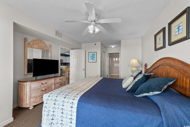 carpeted bedroom featuring ceiling fan and a textured ceiling