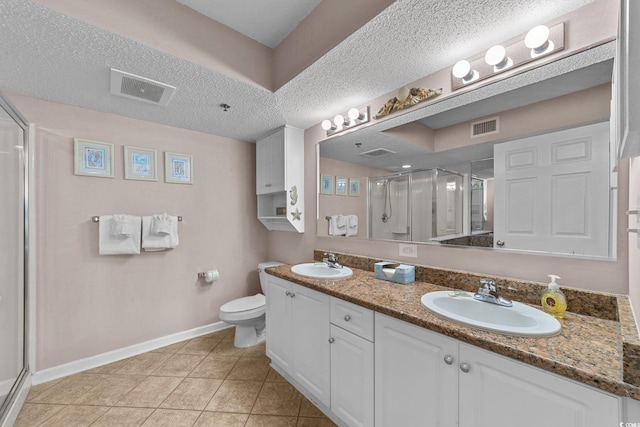 bathroom featuring tile patterned flooring, vanity, a shower with shower door, and a textured ceiling