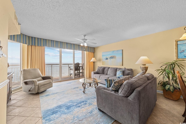 tiled living room with a textured ceiling, a water view, and ceiling fan