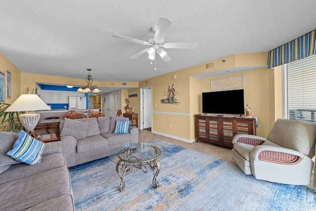 tiled living room with ceiling fan with notable chandelier and a textured ceiling