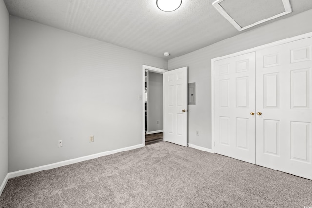 unfurnished bedroom featuring a closet, a textured ceiling, electric panel, and carpet flooring