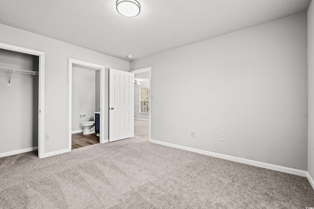 unfurnished bedroom featuring connected bathroom, carpet, a textured ceiling, and a closet