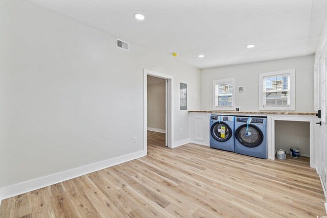 laundry area with light wood-type flooring, electric panel, and washer and clothes dryer