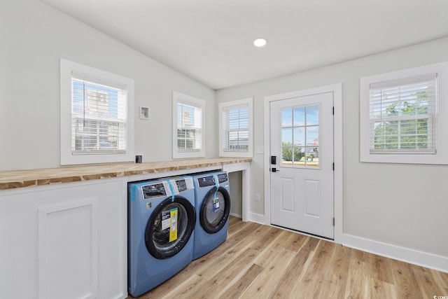 laundry area with light hardwood / wood-style floors and washer and clothes dryer