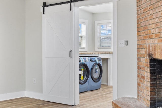 washroom with washer and dryer, a barn door, and light hardwood / wood-style floors