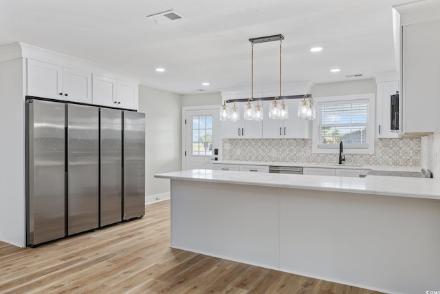 kitchen with pendant lighting, white cabinets, stainless steel appliances, and plenty of natural light