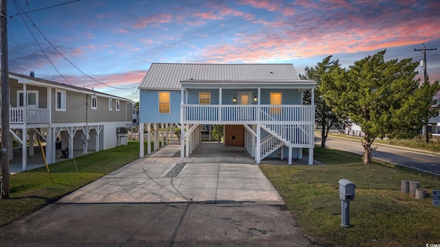 view of front of property featuring a carport, a porch, and a yard