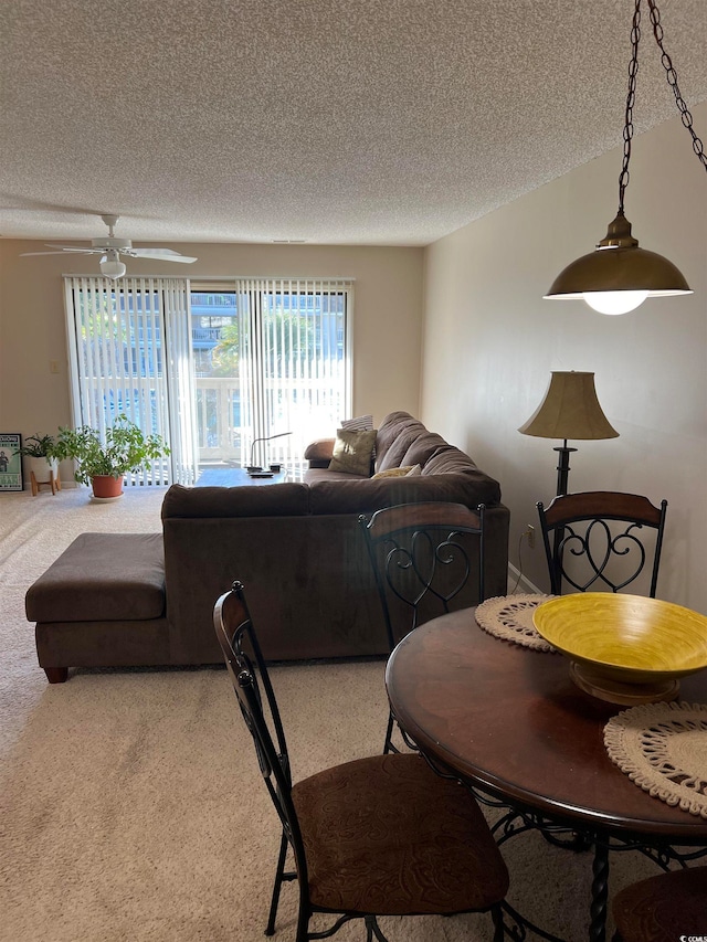 dining area featuring a textured ceiling, carpet, and ceiling fan