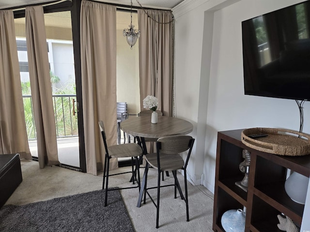 carpeted dining area with crown molding and an inviting chandelier