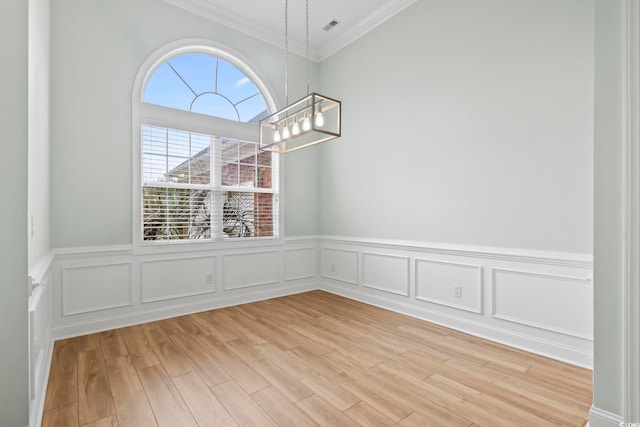 unfurnished dining area featuring crown molding, visible vents, light wood-style flooring, and an inviting chandelier