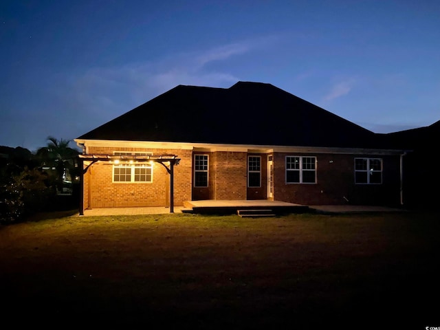 back of property at dusk featuring brick siding