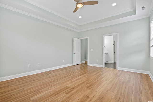 unfurnished bedroom featuring ornamental molding, a tray ceiling, baseboards, and light wood finished floors