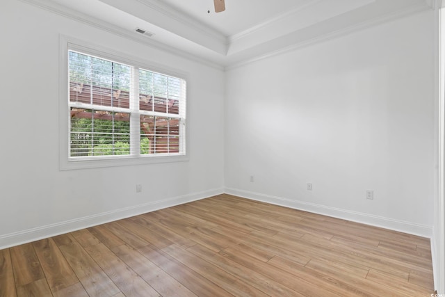 empty room with baseboards, light wood finished floors, visible vents, and crown molding