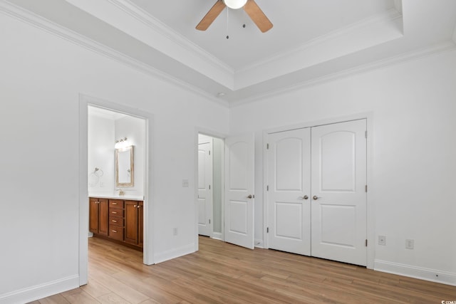 unfurnished bedroom featuring light wood-style floors, a raised ceiling, and crown molding