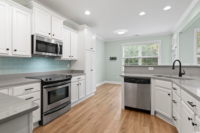 kitchen featuring a sink, appliances with stainless steel finishes, white cabinets, and light countertops