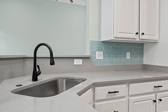 room details featuring light countertops, a sink, white cabinetry, and decorative backsplash