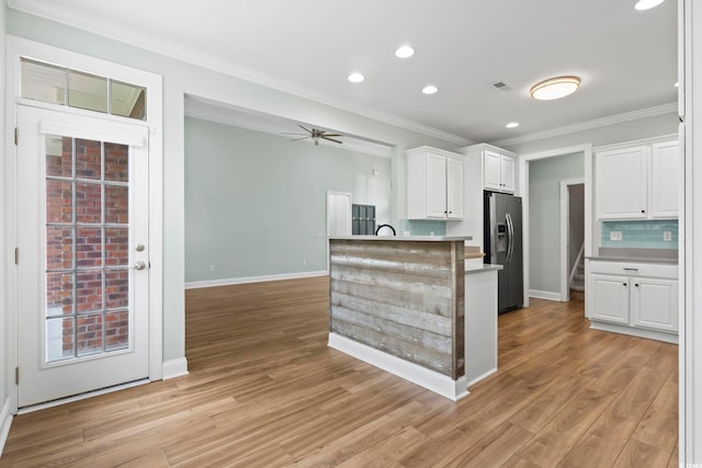 kitchen featuring light wood-style flooring, white cabinets, light countertops, stainless steel refrigerator with ice dispenser, and tasteful backsplash