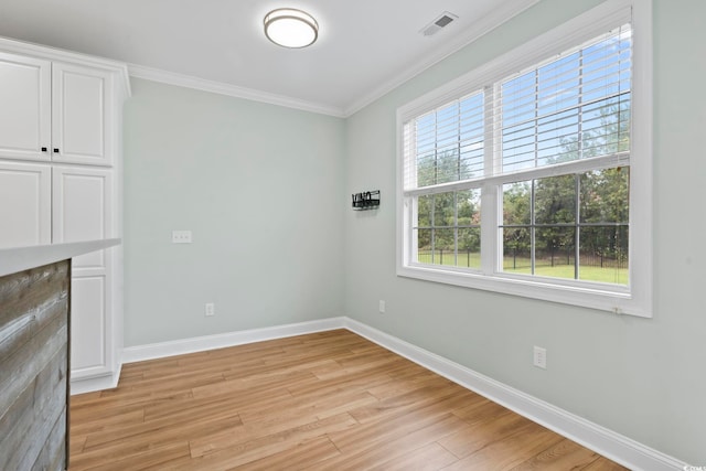 interior space featuring baseboards, crown molding, visible vents, and light wood finished floors