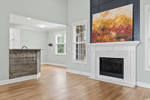 unfurnished living room featuring light wood-style flooring, recessed lighting, a high end fireplace, baseboards, and crown molding