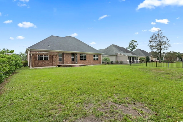 rear view of property featuring a yard, a fenced backyard, and brick siding