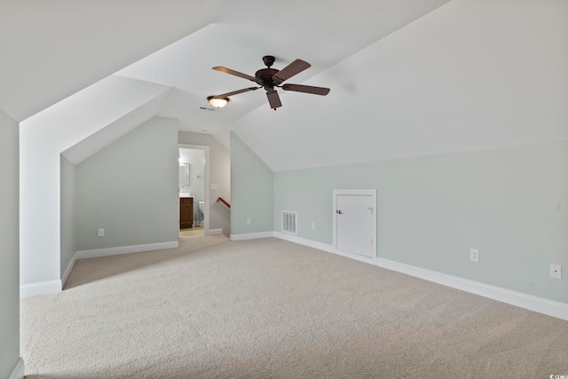 additional living space featuring light colored carpet, visible vents, vaulted ceiling, and baseboards