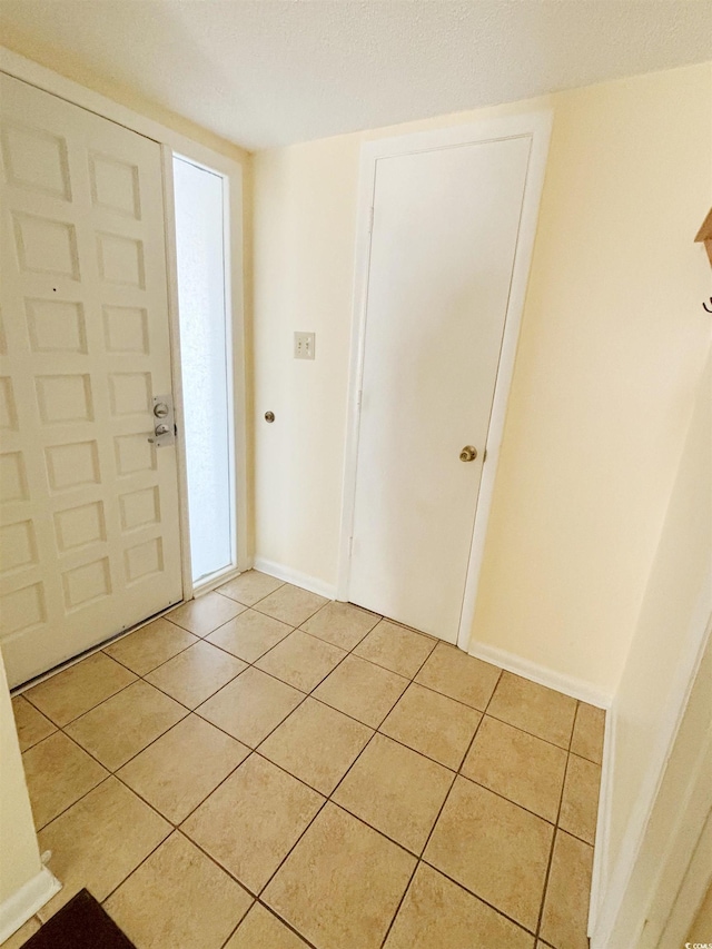 entryway with light tile patterned floors and a textured ceiling