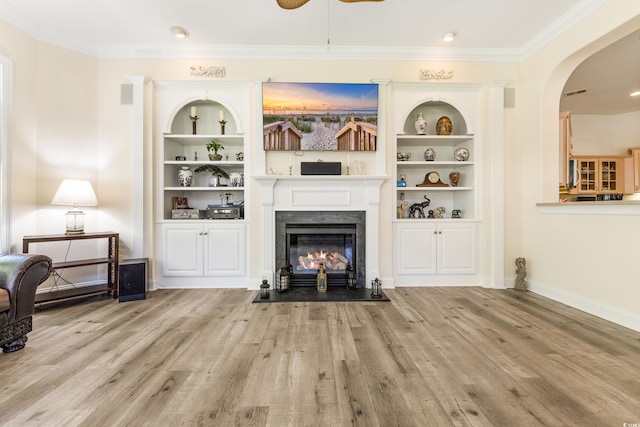 living room featuring light wood-type flooring, crown molding, and built in features