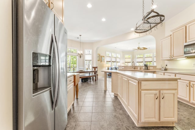 kitchen with light tile patterned flooring, kitchen peninsula, a kitchen island, decorative light fixtures, and appliances with stainless steel finishes